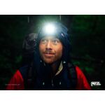 Portrét turisty s nasazenou čelovkou Petzl TIKKA CORE v dešti při večerním treku - E067AA00